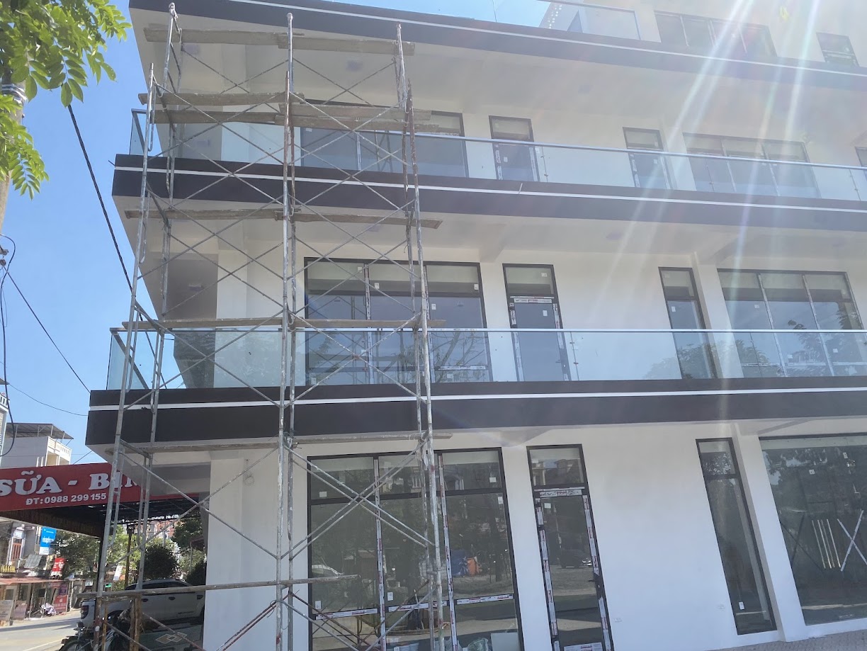 Nhà phố 3 tầng đang thi công với lan can kính cường lực với cửa nhôm kính và giàn giáo phía trước